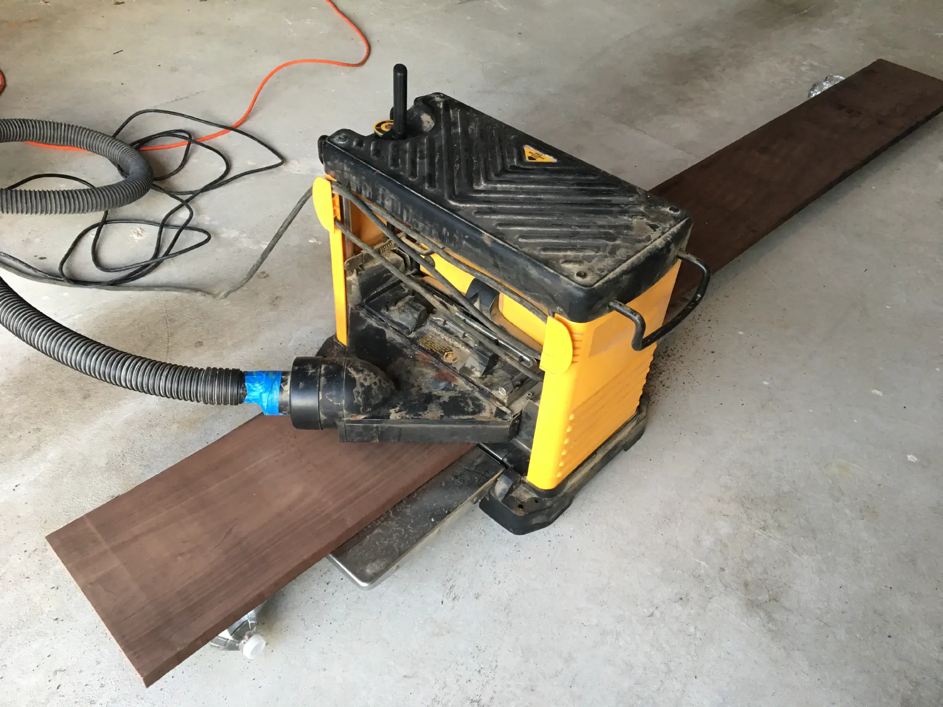 Walnut hardwood board part way through a thickness planer