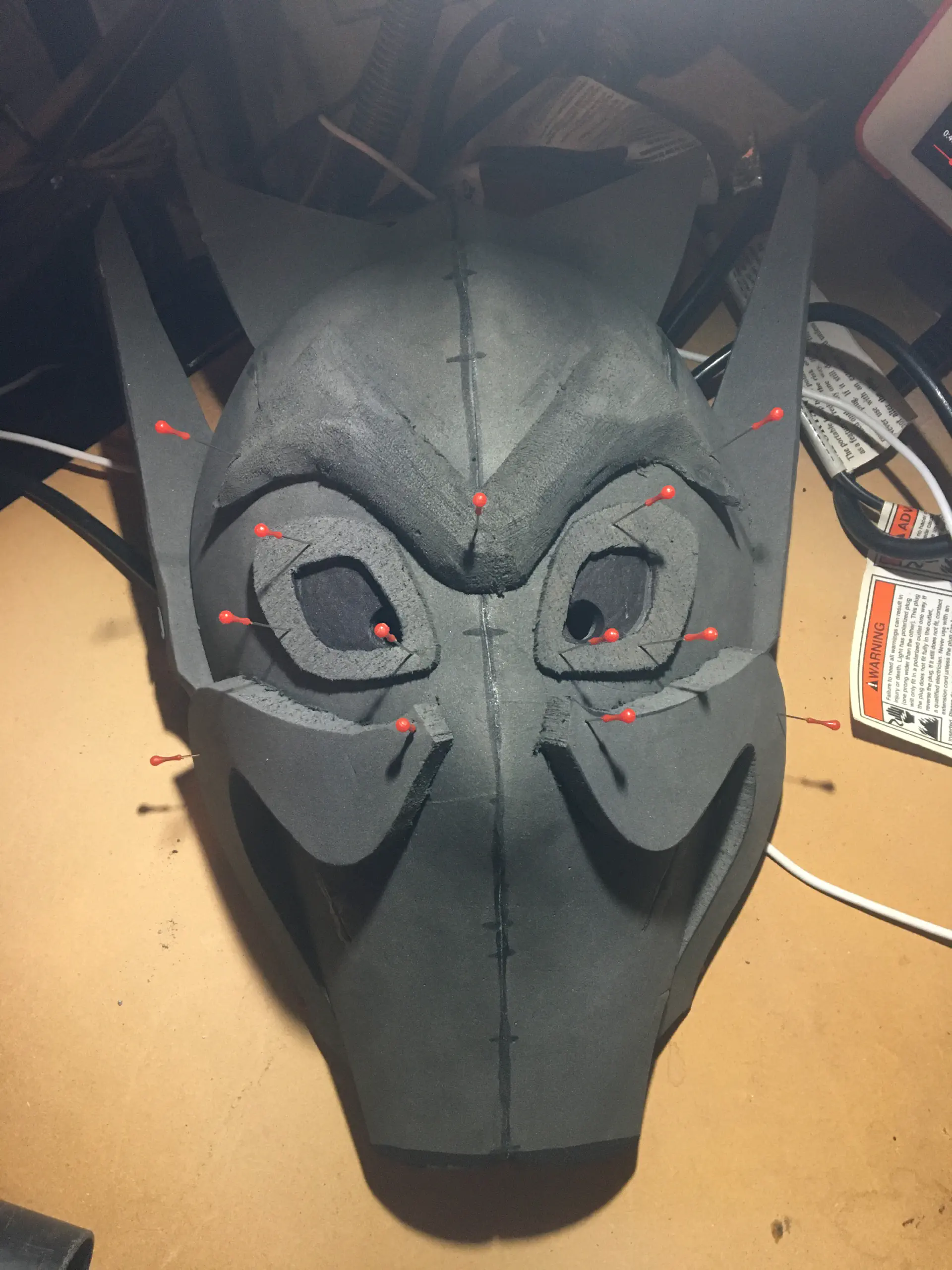 With the eyebrow and eyes pinned on, a mustache piece is cut out and pinned on either side of the mask.