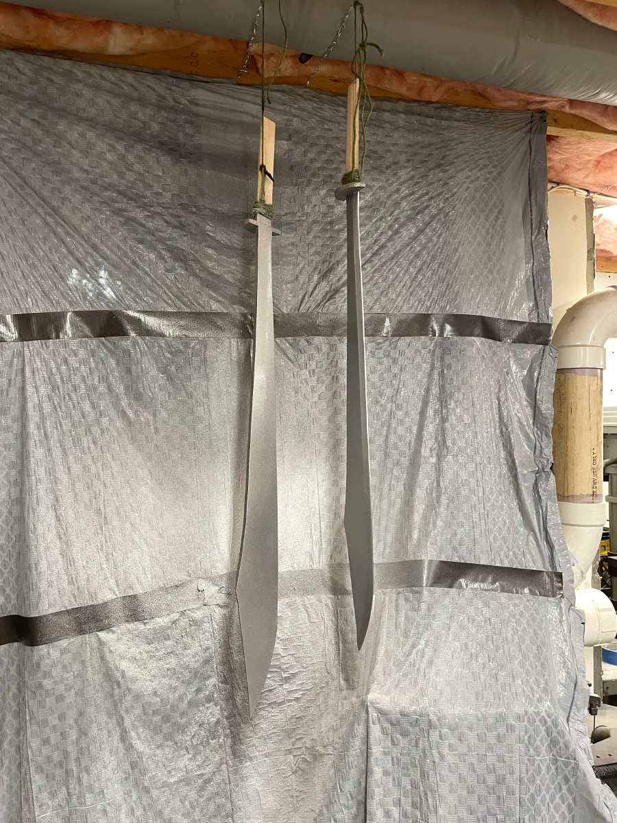 Using silver spray paint, the swords hang with the blades painted. The guard and hilt aren't finished.